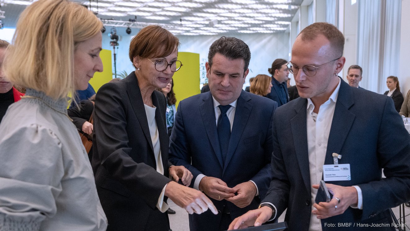 Eine Gruppe von vier Personen schaut auf ein Tablet.