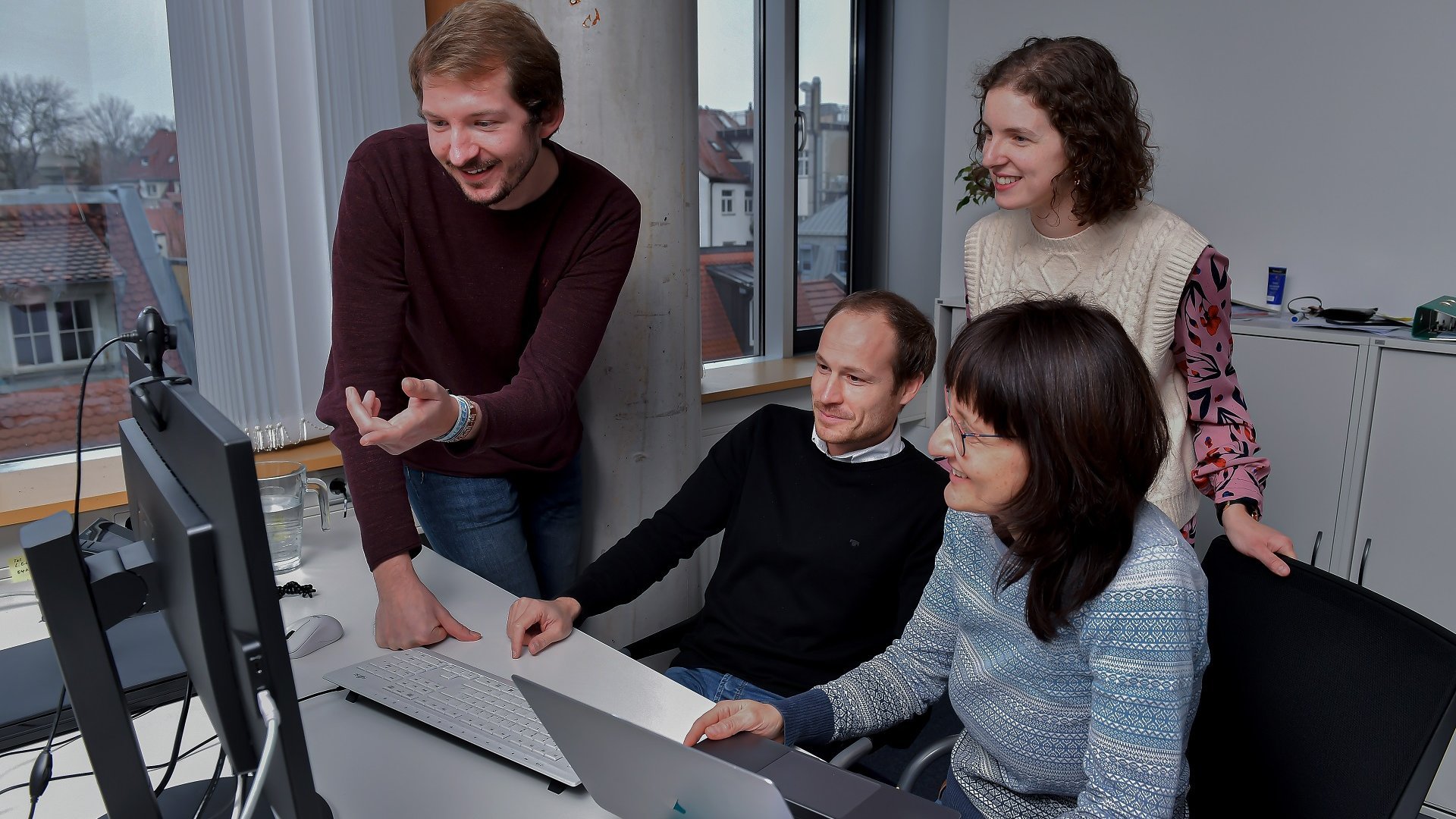 Vier Mitarbeitende im Büro, die konzentriert auf den Bildschirm schauen.