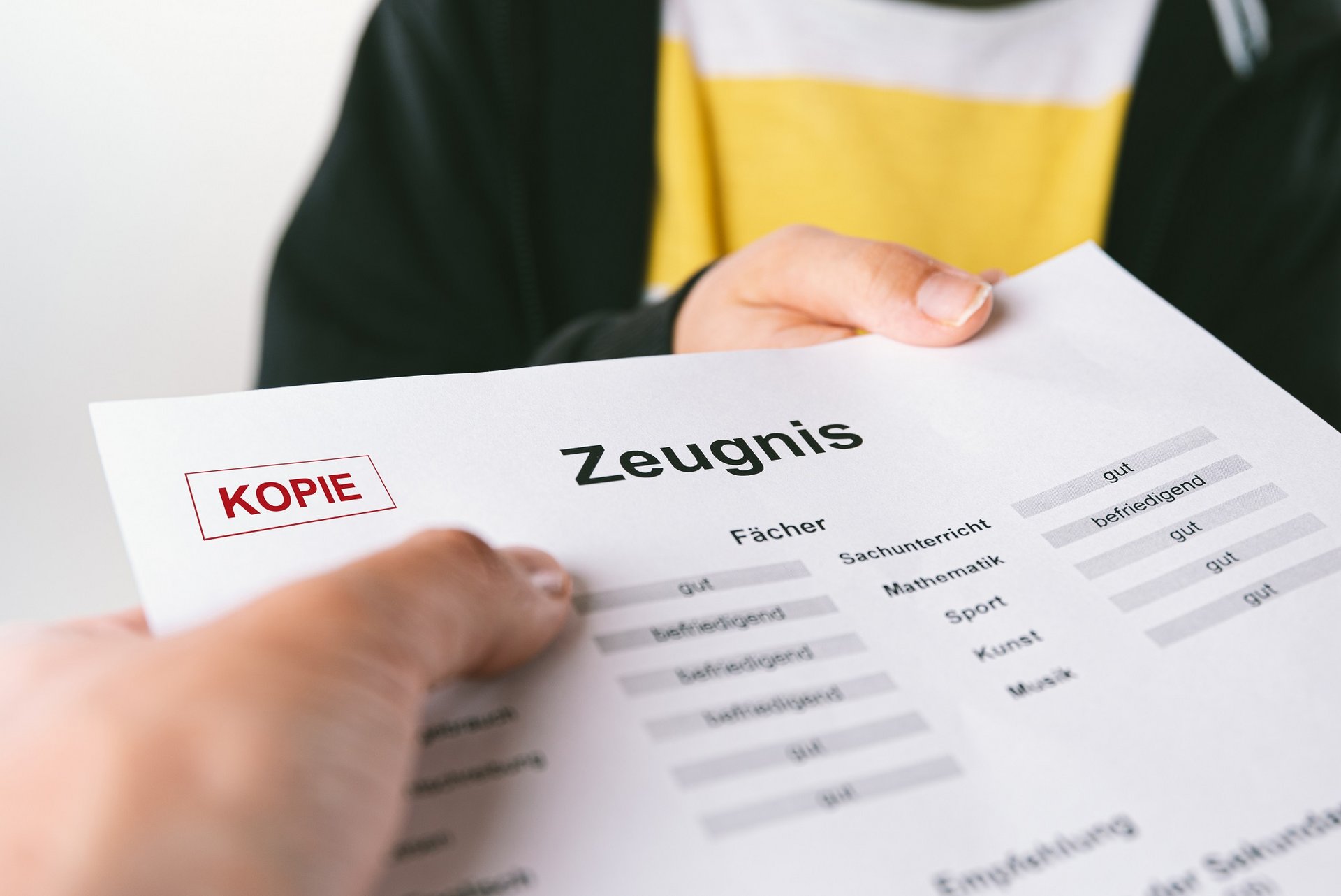 Ein Schulkind bekommt sein Zeugnis überreicht.