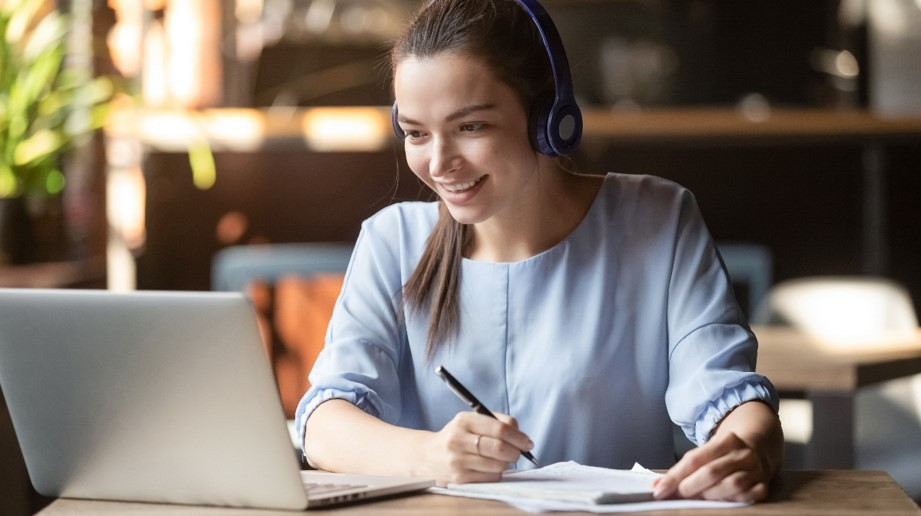 Eine junge Frau sitzt arbeitend vor ihrem Laptop.