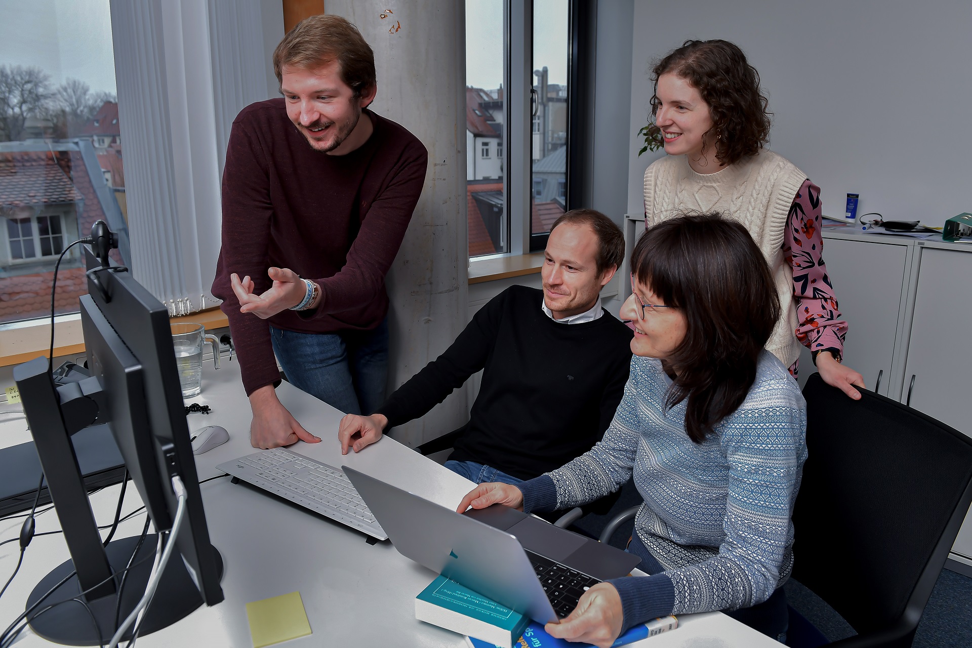 Vier Mitarbeitende im Büro, die konzentriert auf den Bildschirm schauen.
