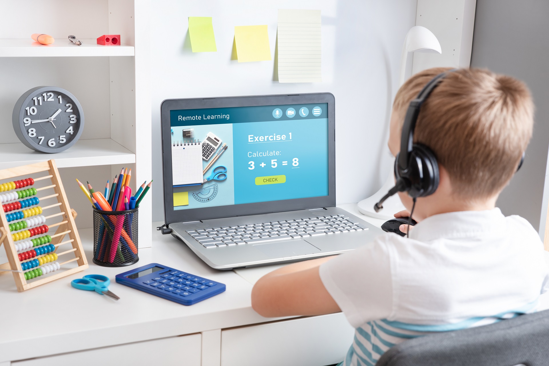 Ein Junge sitzt konzentriert in seinem Kinderzimmer vor einem Laptop. Auf dem Bildschirm ist das Wort "Remote Learning" zu sehen, was auf das virtuelle Lernen hinweist.